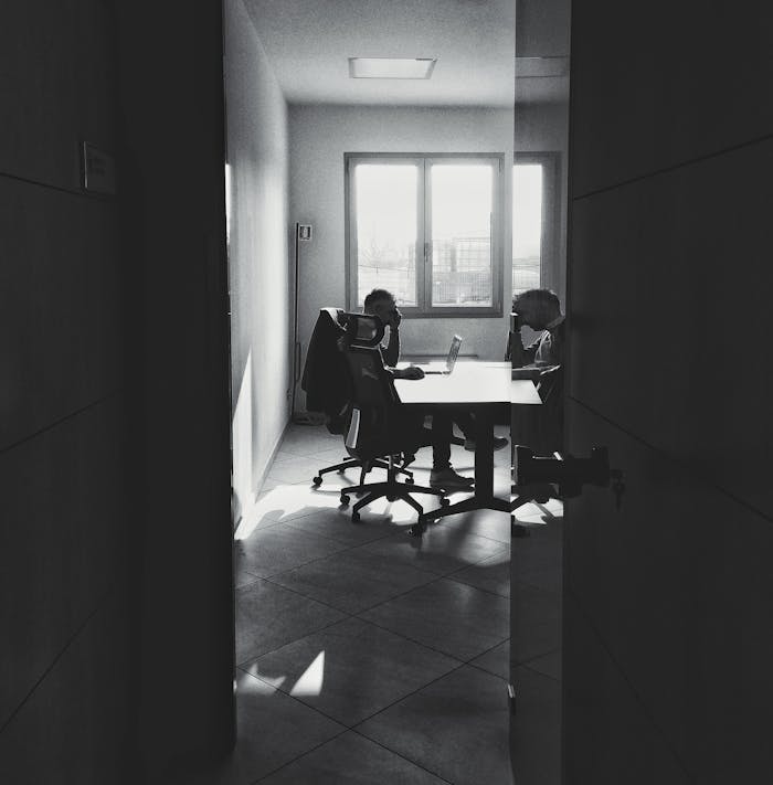 Monochrome image of two individuals working in a minimal office setting.